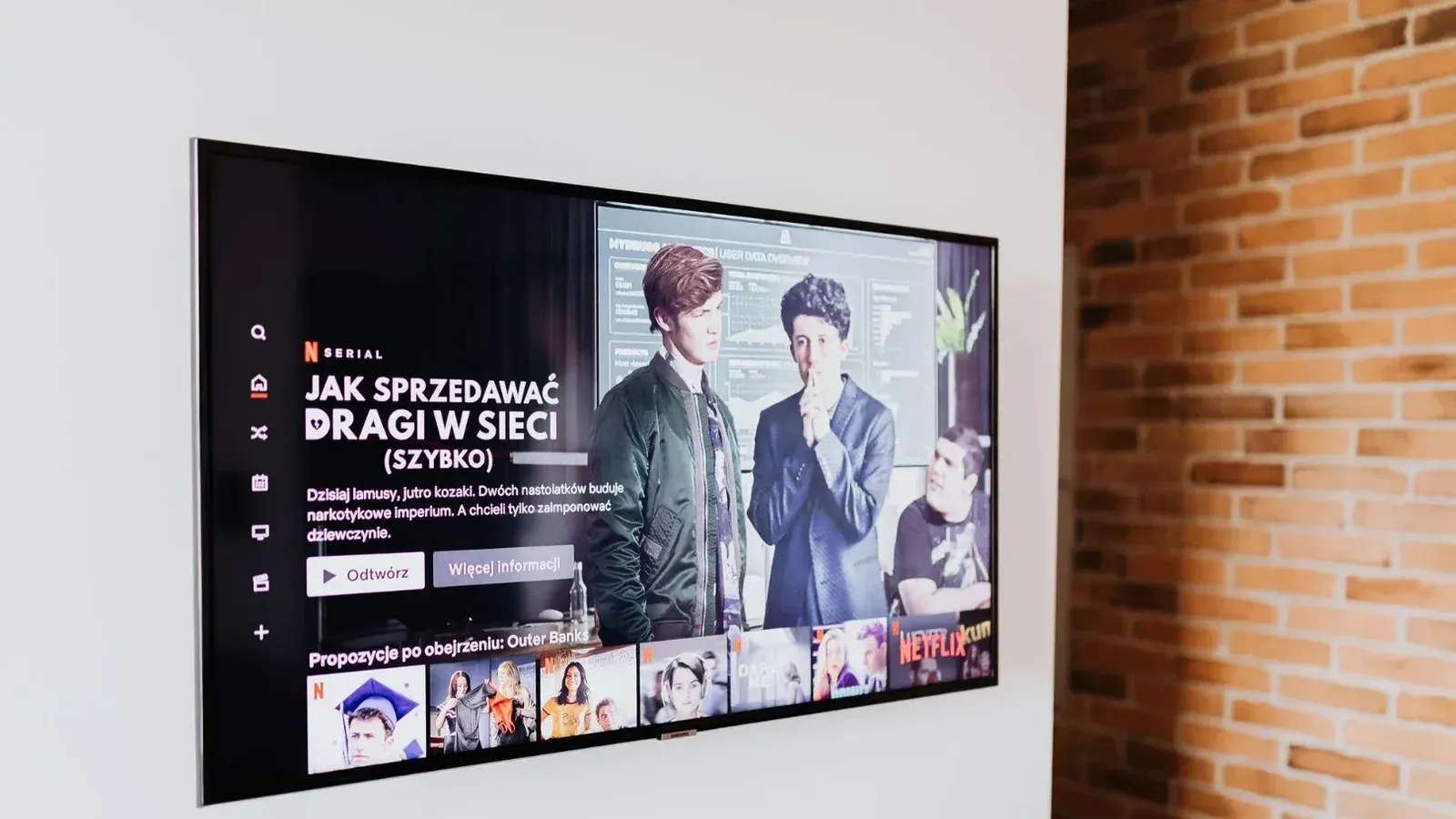 Smart TV displaying streaming content in modern living room setting with exposed brick wall.