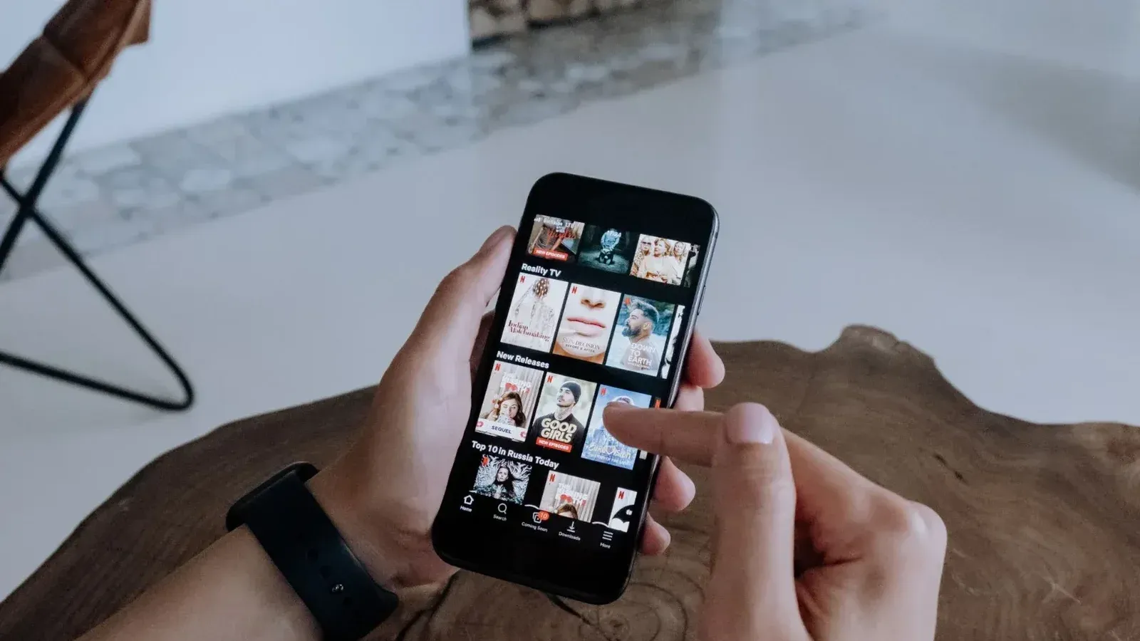 A person using a smartphone to explore and select shows on a streaming platform indoors.