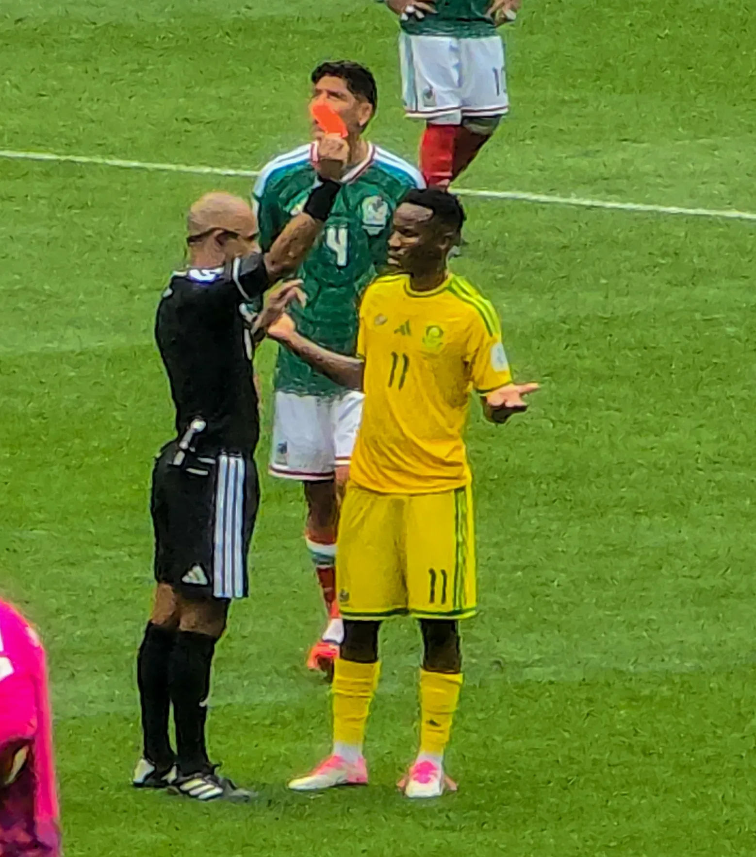 Un árbitro levanta una tarjeta roja ante un jugador de Sudáfrica con el número 11, mientras un jugador de México con el número 4 observa detrás.