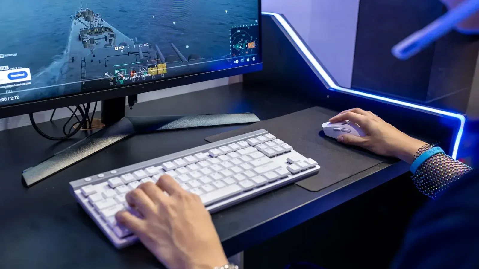 Primer plano de una persona que juega en una PC con una colorida configuración y accesorios de juego.
