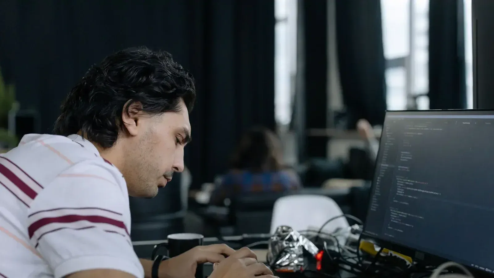 A coder intensely typing at a workstation in a contemporary office setup.