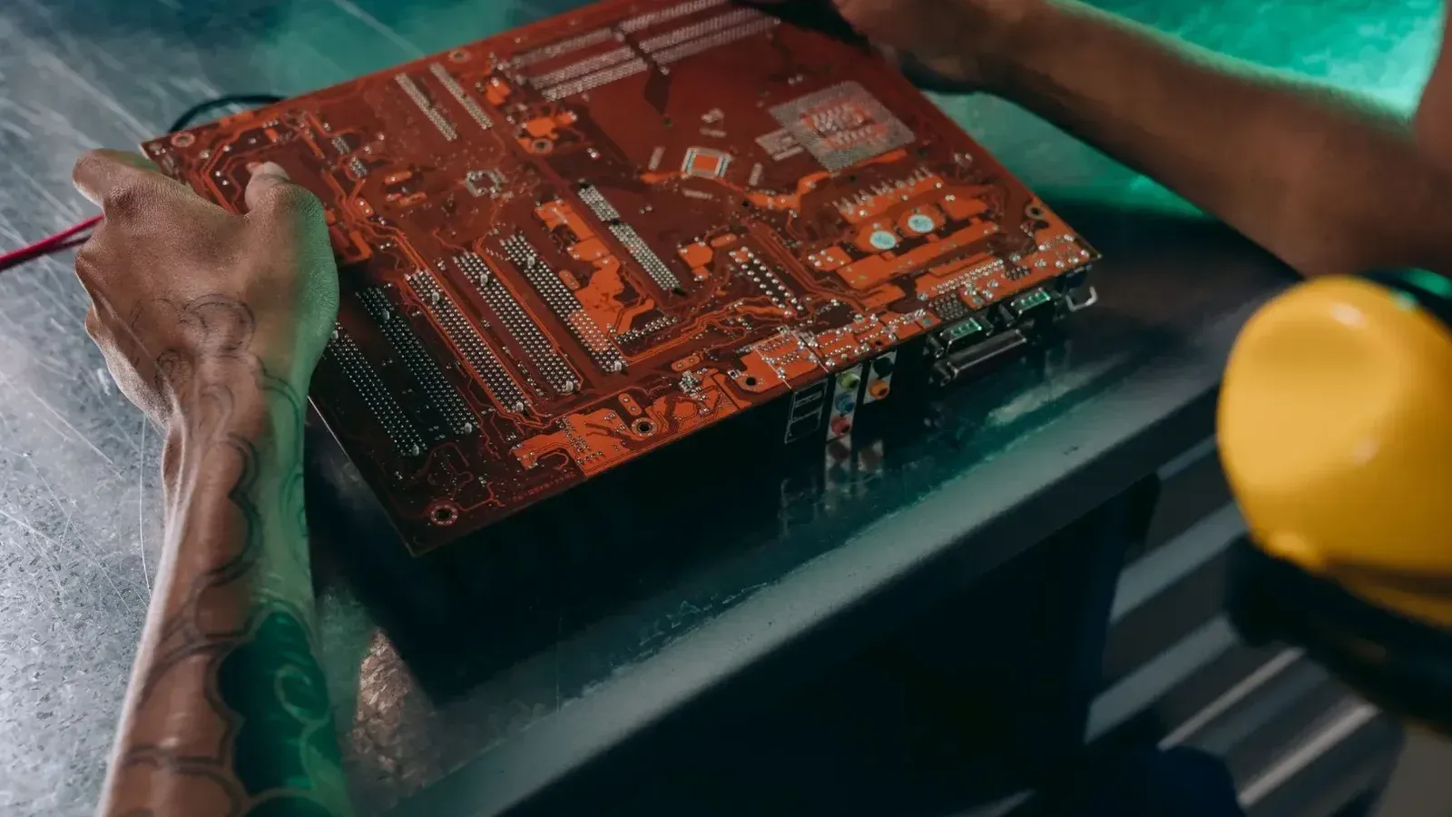 Primer plano de un técnico que trabaja en una placa de circuito en un entorno industrial.