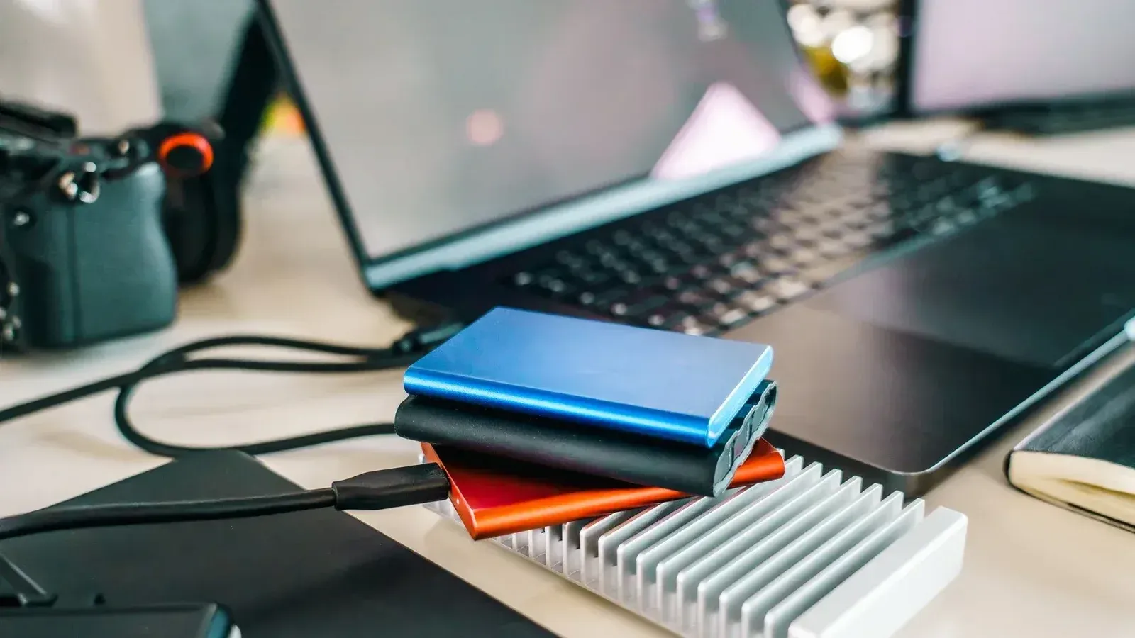 A contemporary office setup showcasing external hard drives, laptop, and camera for efficient data management.