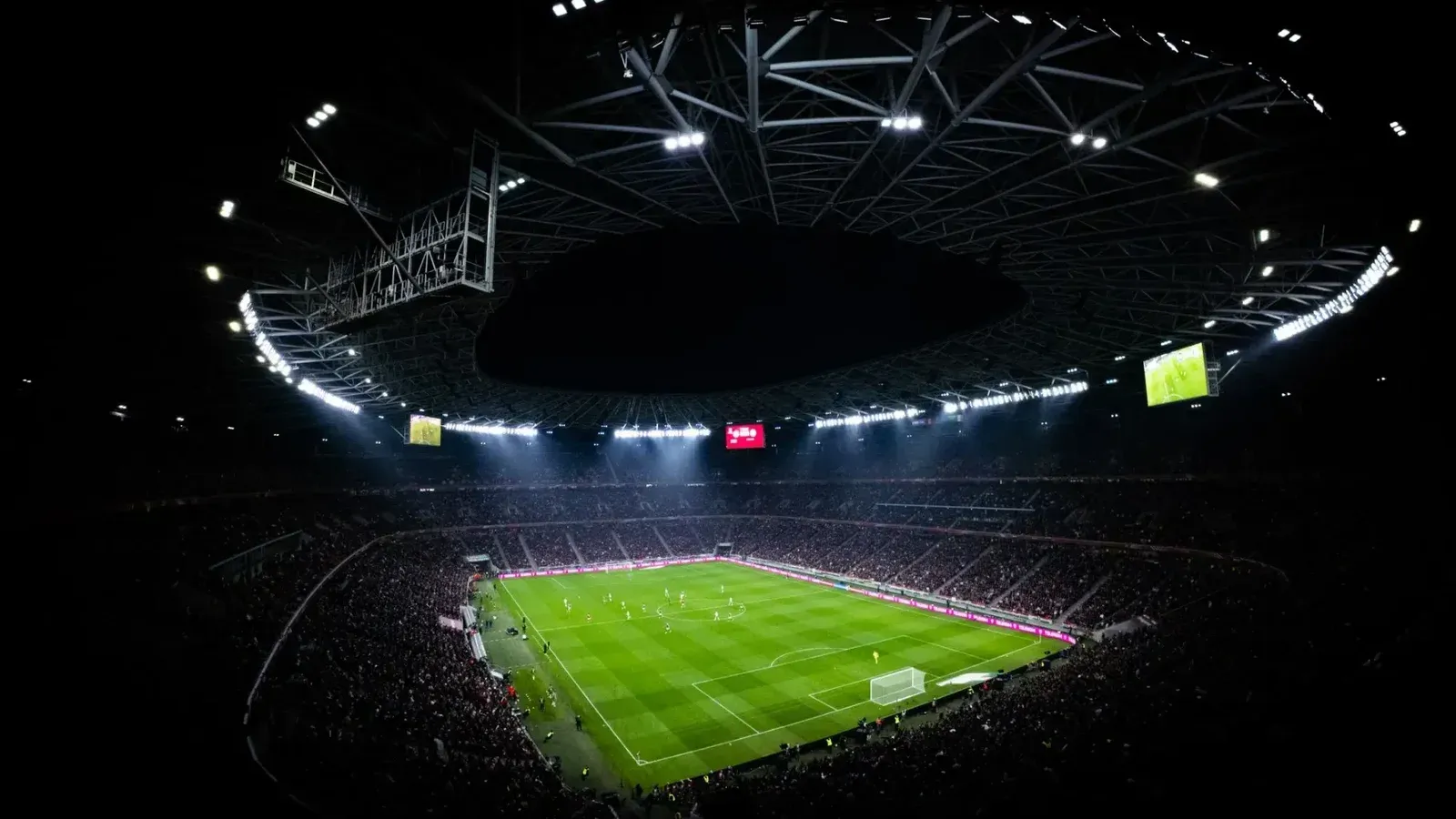 Vista aérea de un partido de fútbol nocturno en Budapest. Estadio iluminado lleno de fans añade un ambiente dramático.