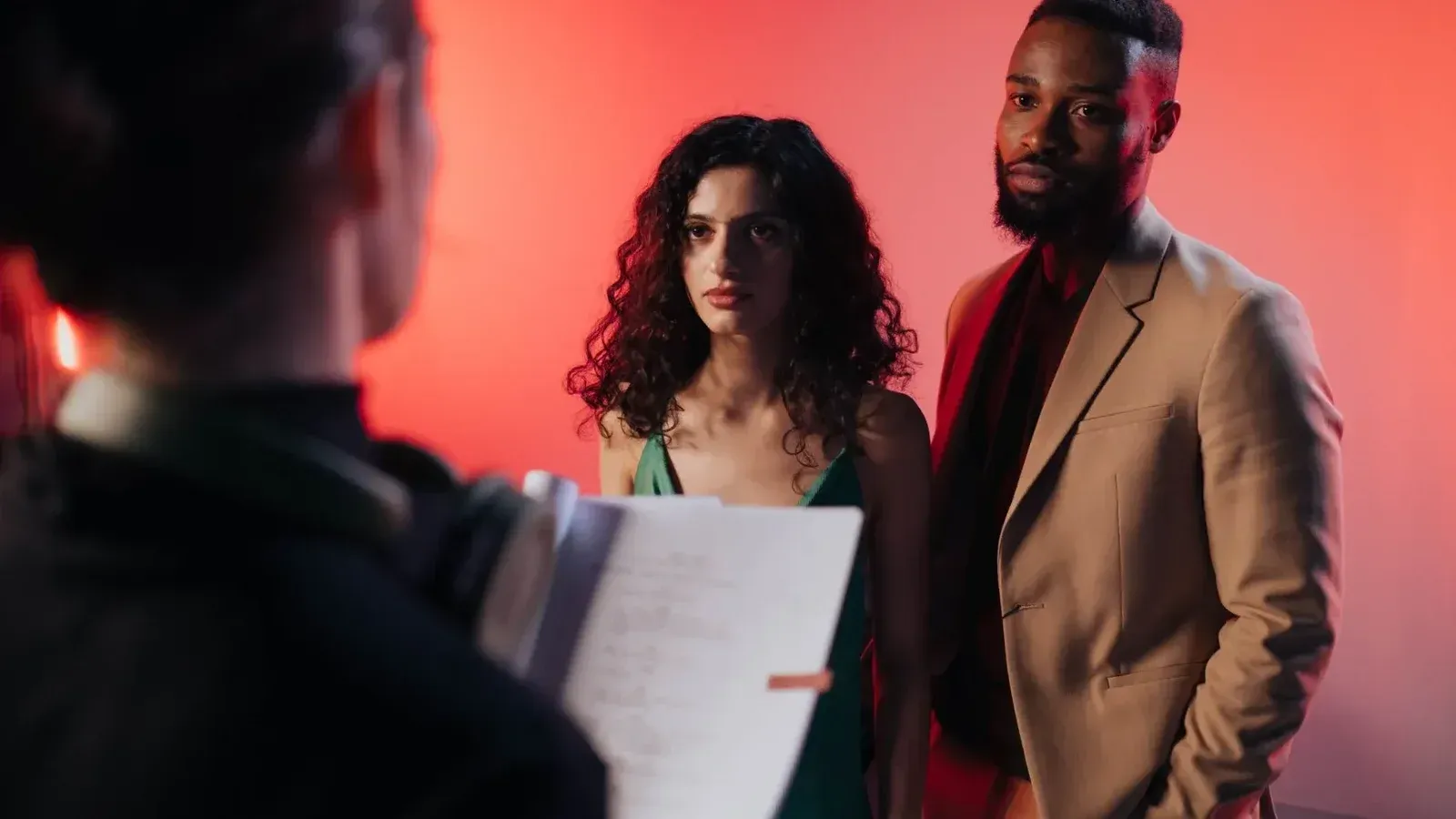 Couple reading script in a studio with warm lighting for film or theater production.