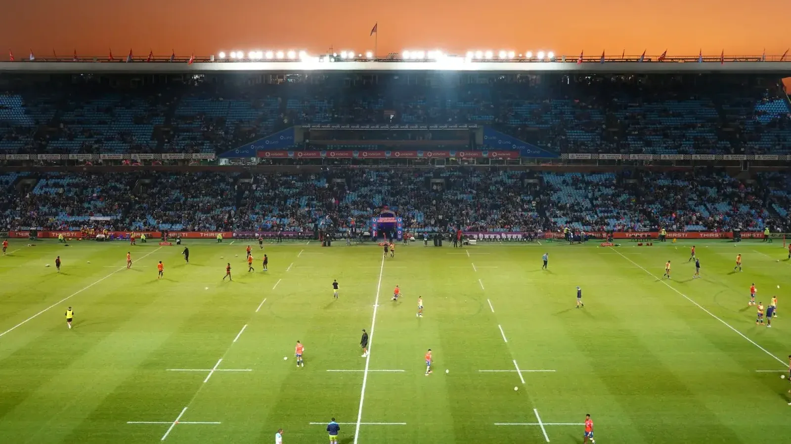 Emocionante juego de rugby desplegando bajo una impresionante puesta de sol en un gran estadio.