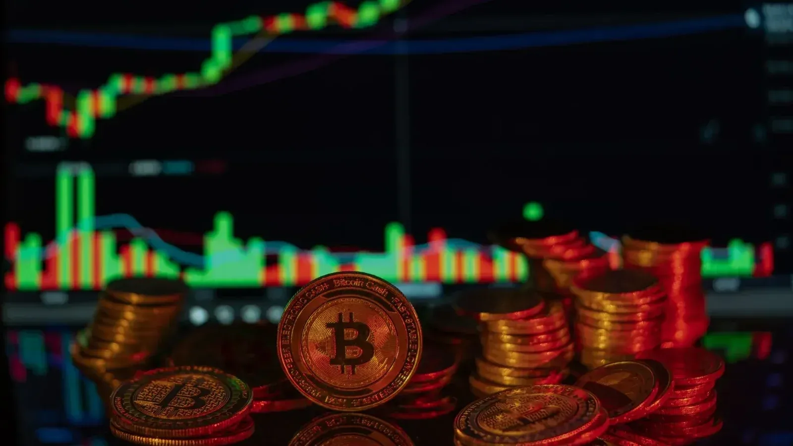 Pilas de monedas de Bitcoin con un gráfico del mercado financiero en el fondo, que representa el comercio de criptomonedas.