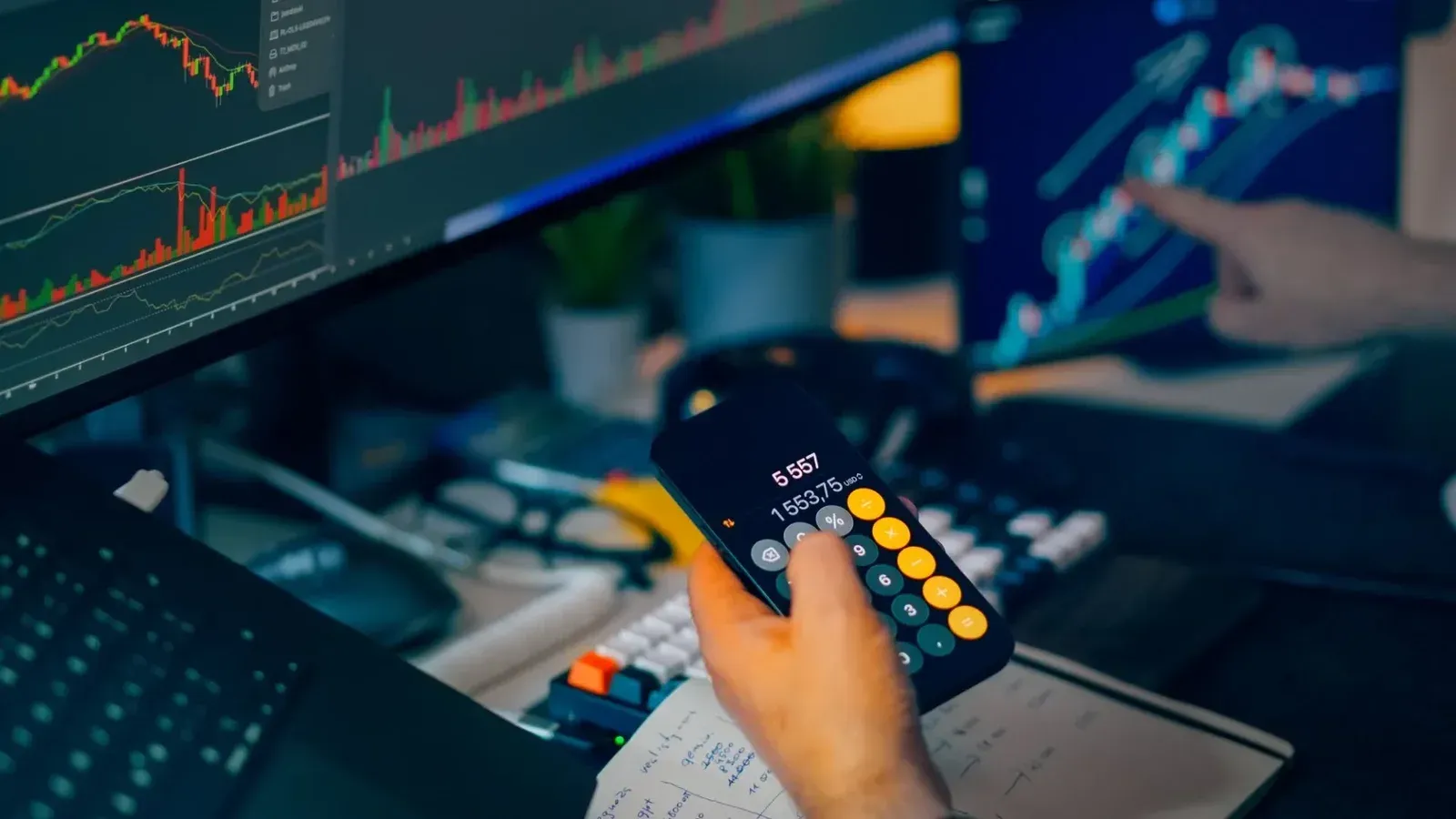 Una toma enfocada del comercio financiero con pantallas, calculadora y gráficos de datos.