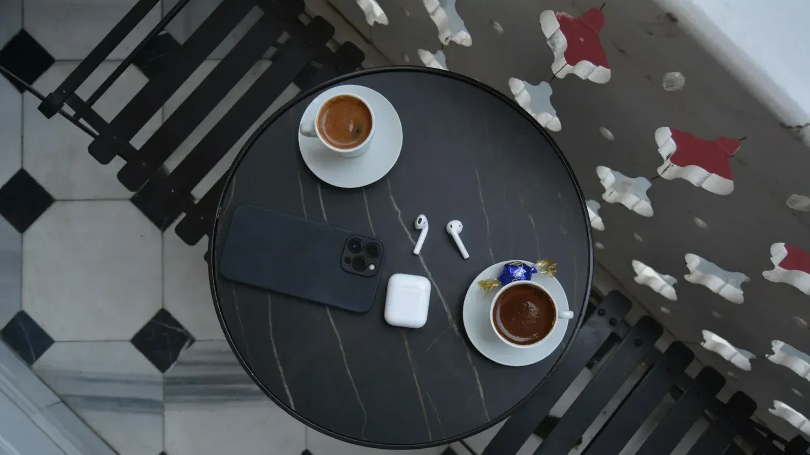Vista superior de una mesa de café con café, teléfono inteligente y auriculares inalámbricos.