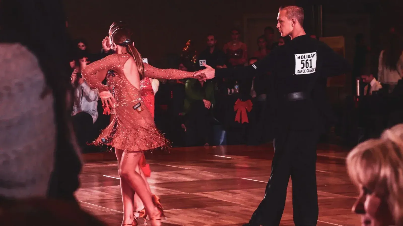 Una pareja realiza una graciosa rutina de baile de salón en el escenario durante un animado evento de competición.