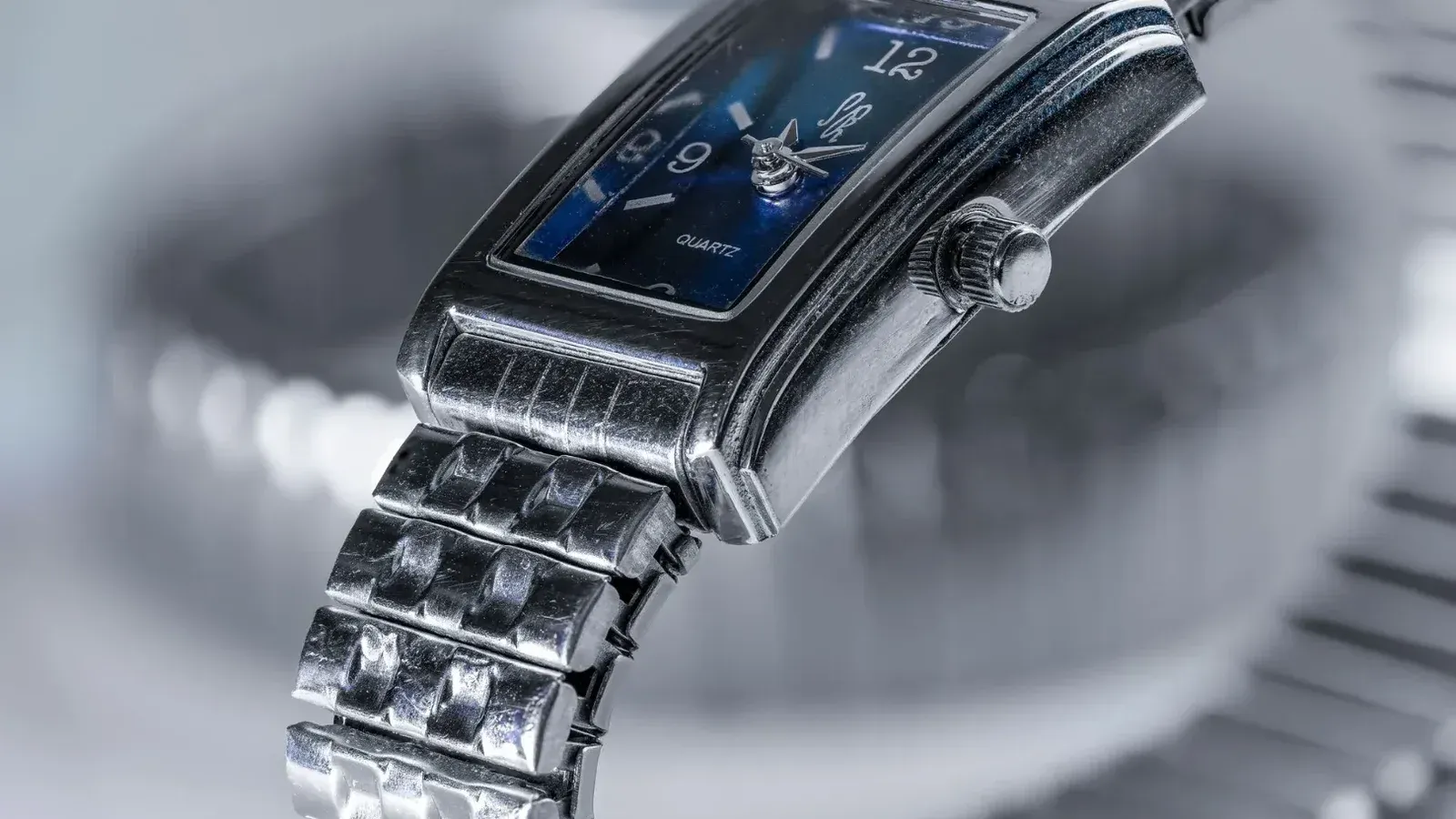 Imagen detallada de un clásico reloj de pulsera de cuarzo plateado que muestra su esfera azul y pulsera de metal.
