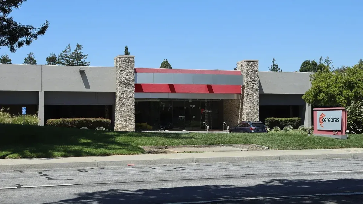 Edificio de oficinas de una planta en Sunnyvale, California, con una franja roja sobre la entrada y un letrero rojo y blanco con el logotipo de Cerebras sobre el césped, junto a la calle
