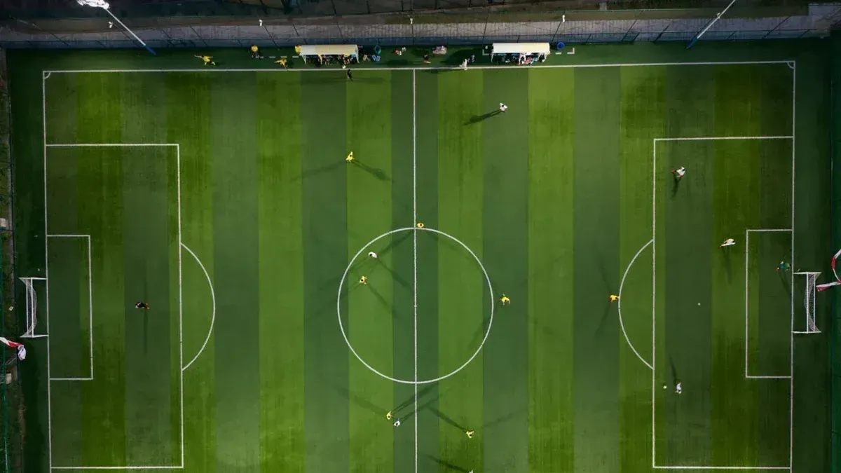 Dynamic aerial shot capturing a soccer match on a vibrant green field at night.