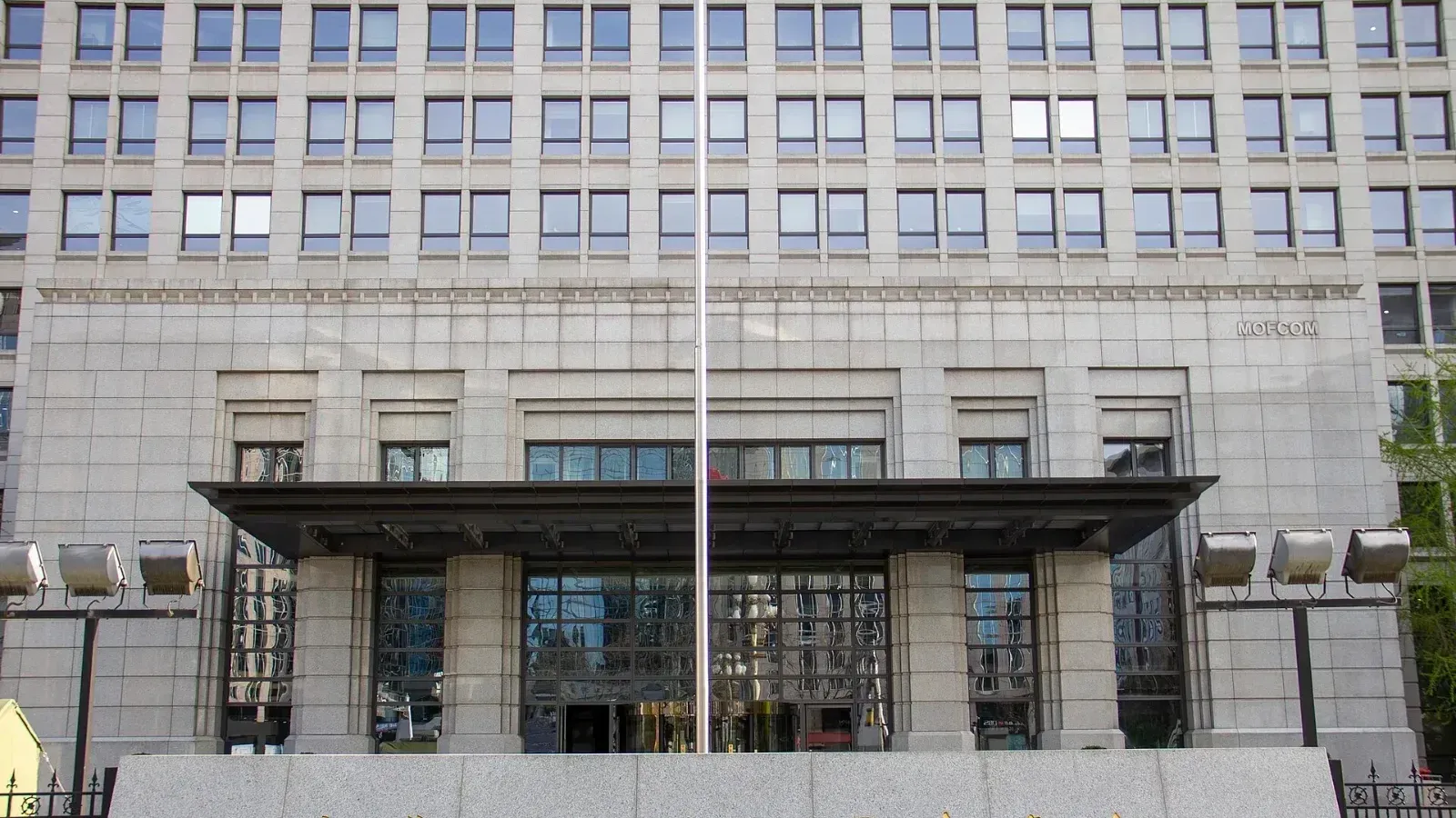 Fachada del edificio del Ministerio de Comercio de China, con su nombre en caracteres chinos tallado en un muro de piedra al frente y la palabra MOFCOM en la pared.