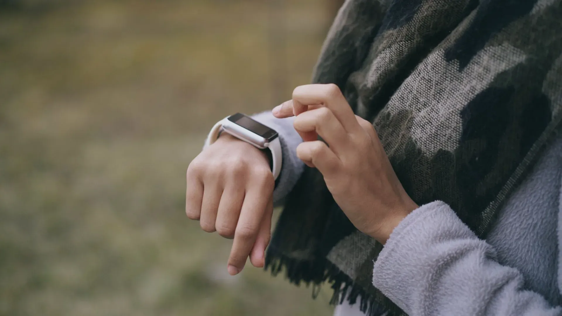 Close-up of a person using a smartwatch outside.