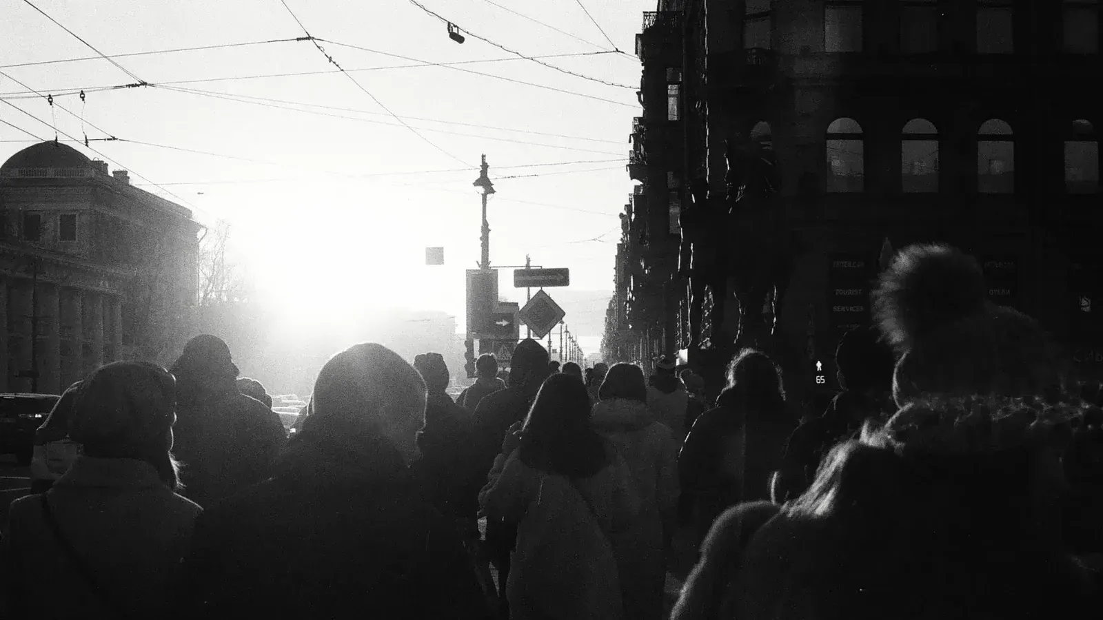 Silhouettes of people walking in a city street during sunrise with a vintage, moody tone.