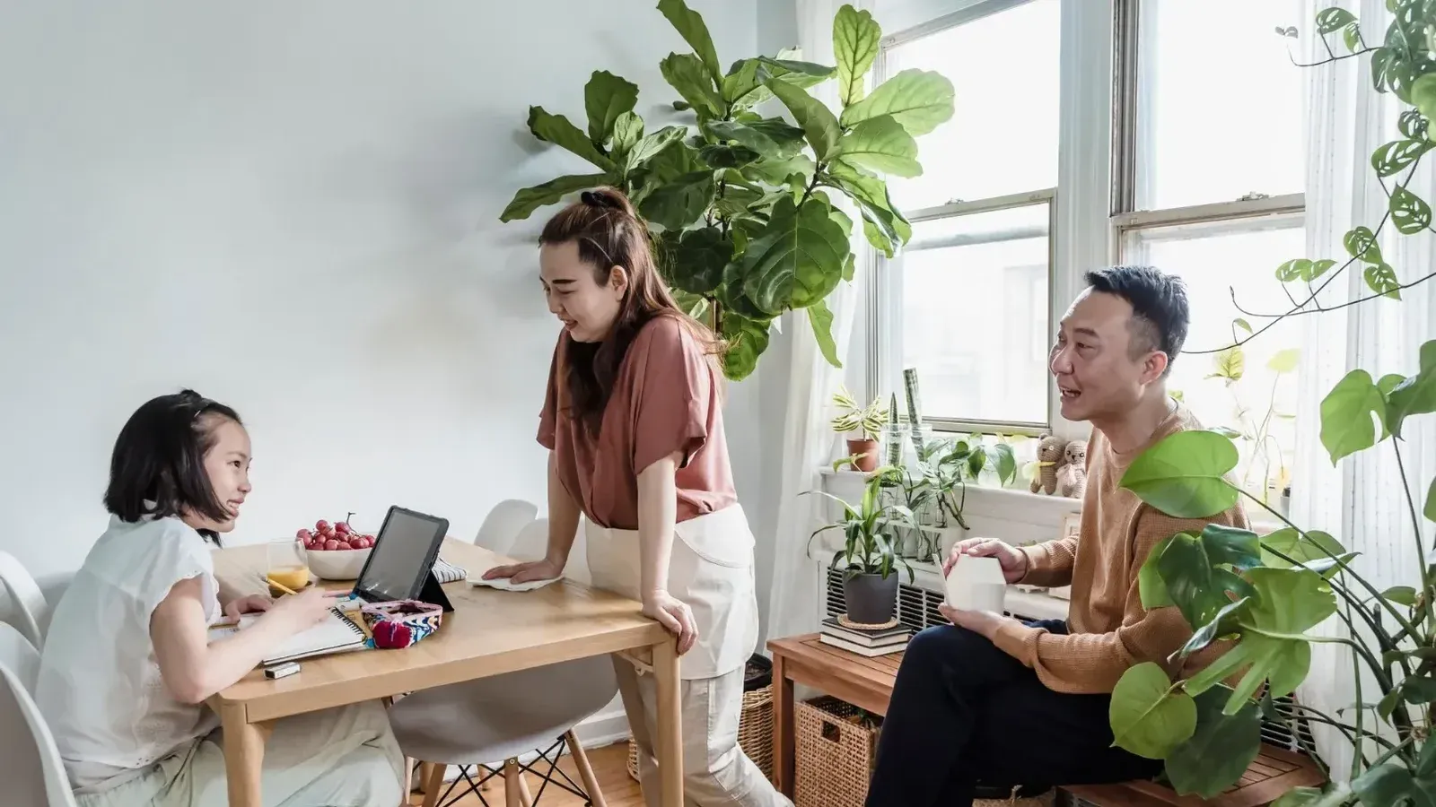 Family spending quality time together as daughter does homework at dining table.