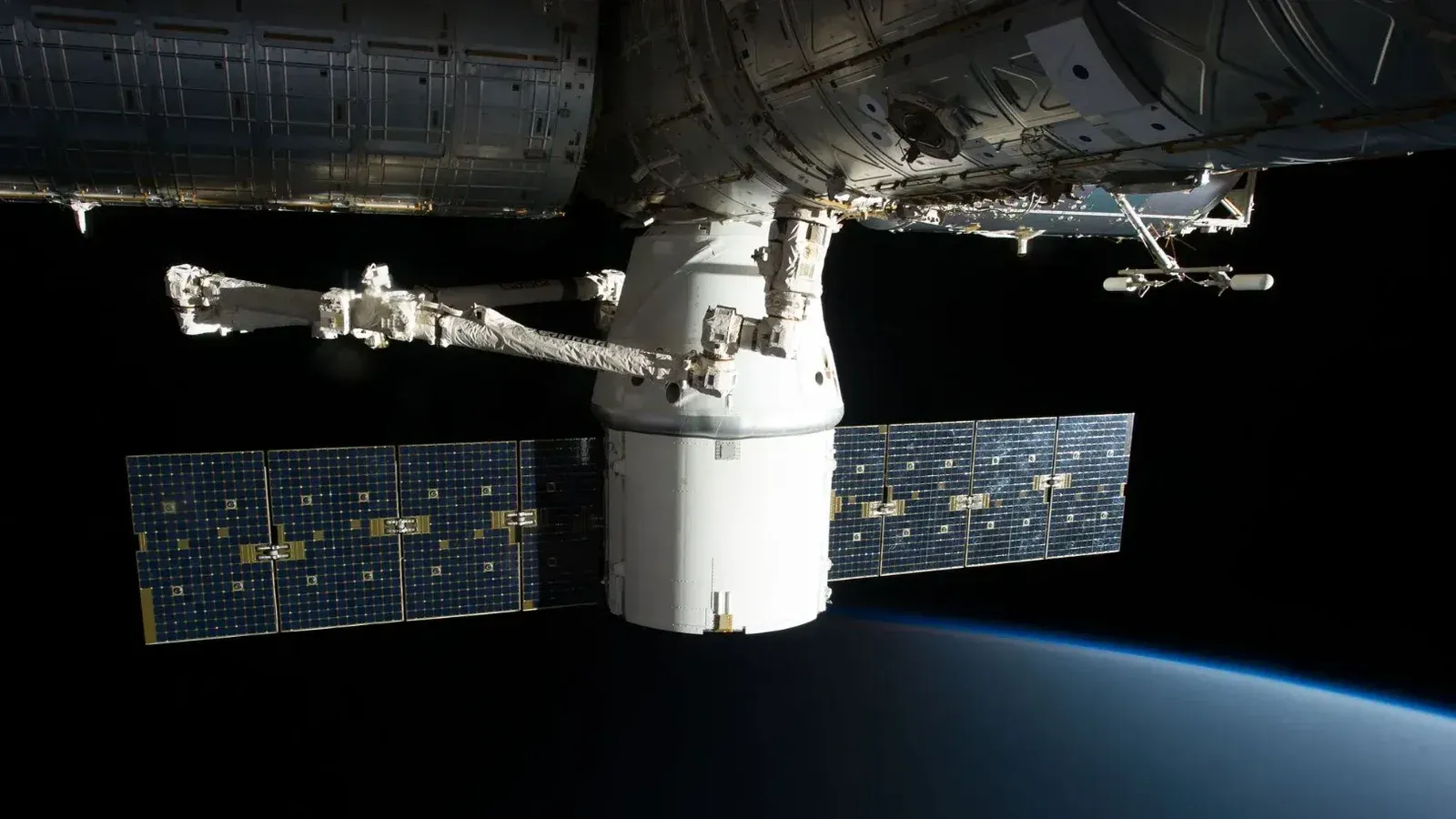 Imagen de la Estación Espacial Internacional flotando sobre la Tierra con paneles solares visibles.
