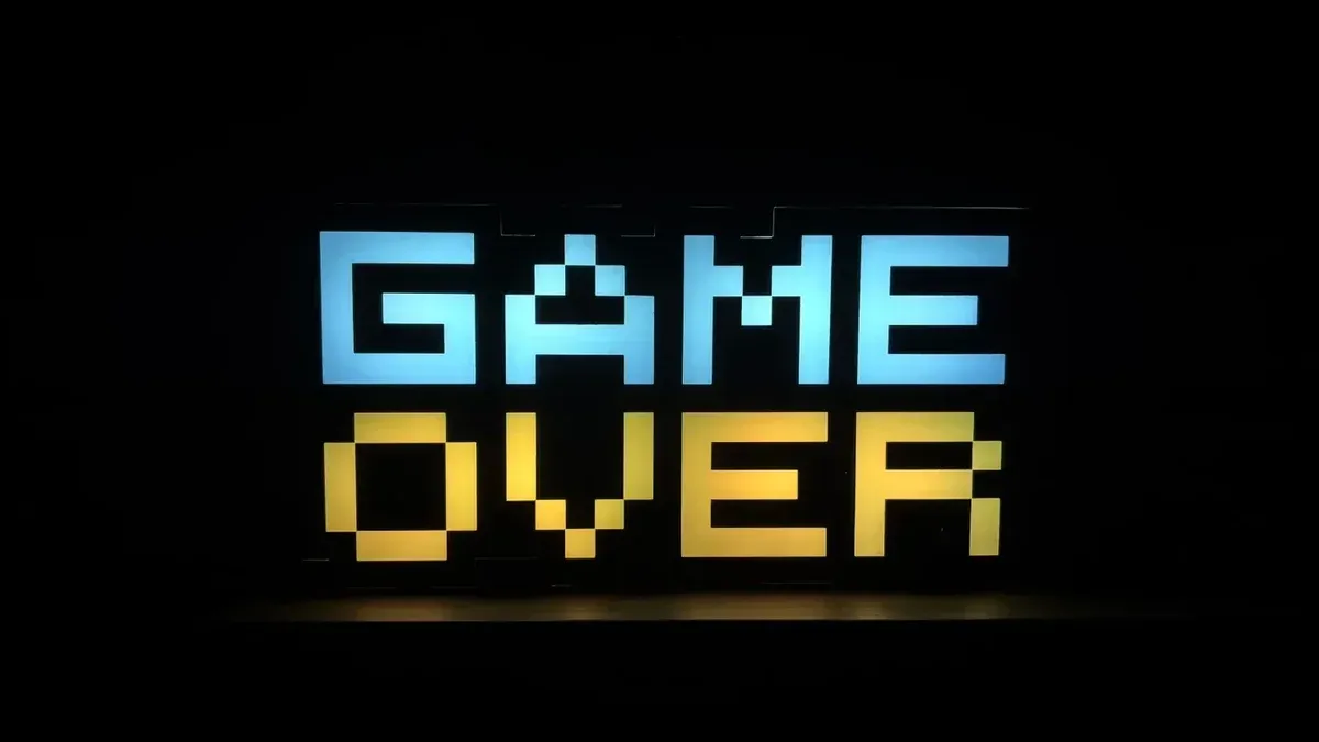 Illuminated pixel art 'Game Over' sign with vibrant colors against a black background.