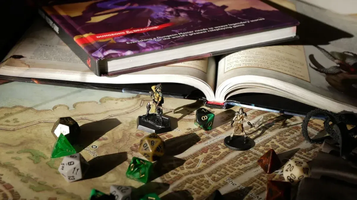 Primer plano de la configuración de RPG de mesa con libros, dados y figuritas en un mapa.