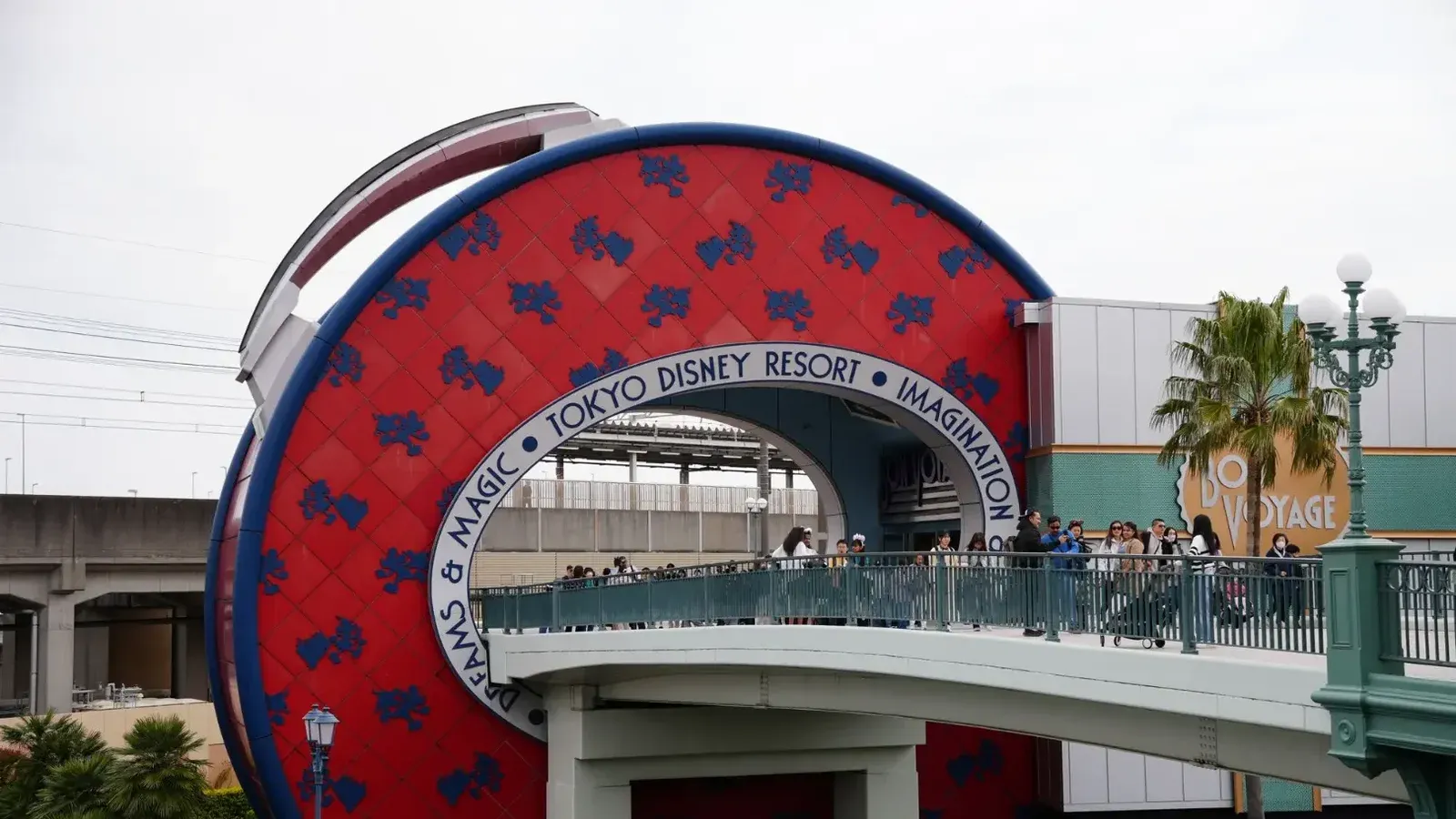 Captura de la entrada de Tokyo Disney Resort con la tienda Bon Voyage y el puente peatonal.