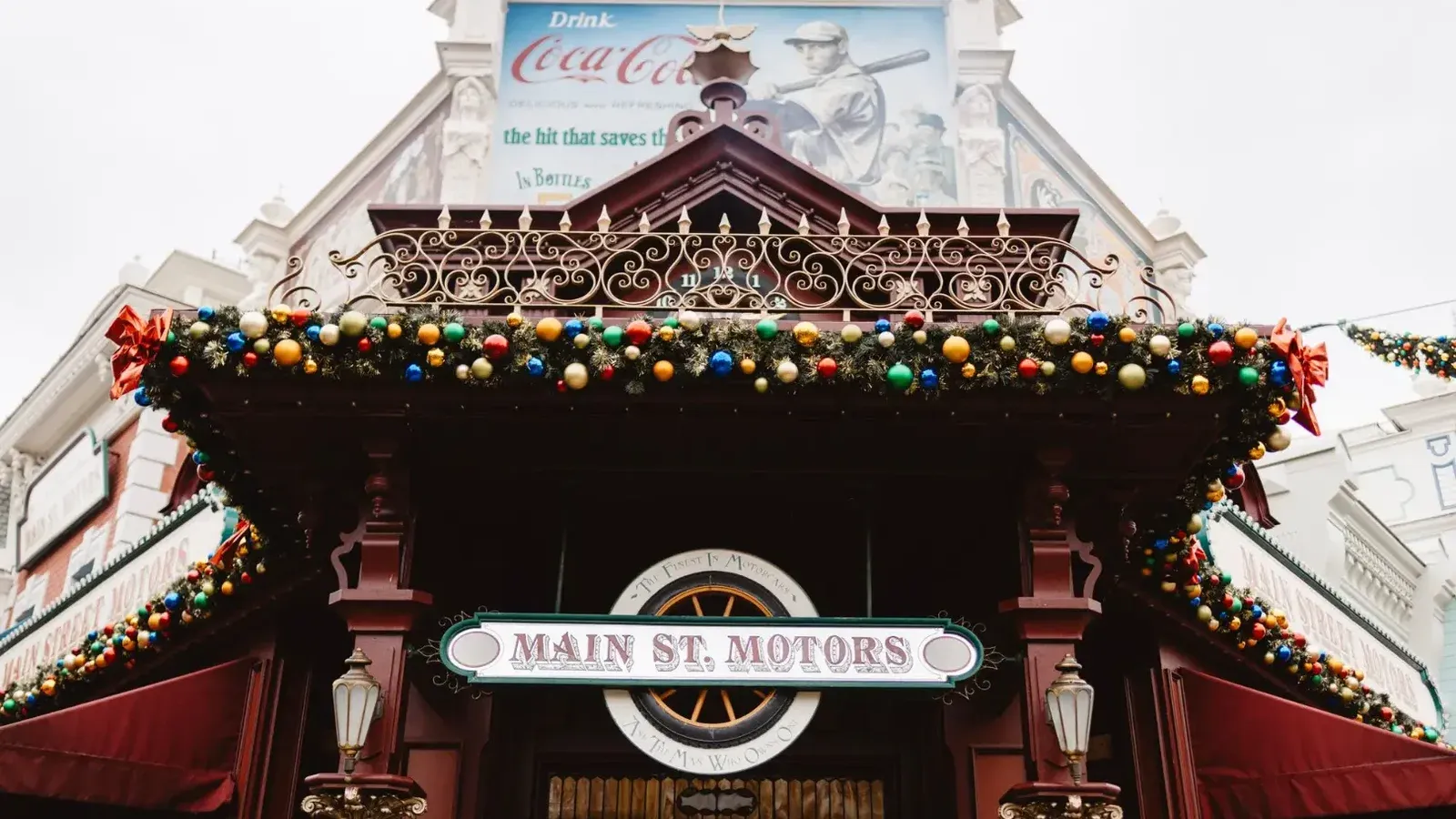 A festive view of 'Main St. Motors' adorned with colorful baubles and holiday decor in Paris, France.