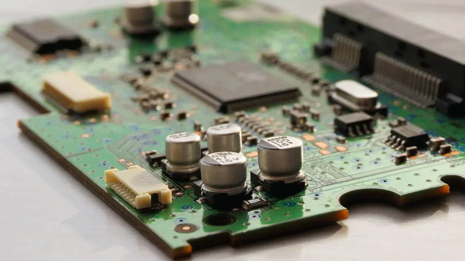 Detailed view of a green circuit board featuring capacitors and microchips.
