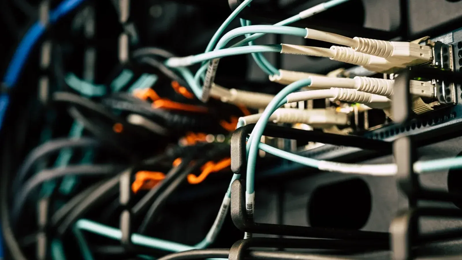 Varios cables enredados conectados al sistema cerca de cajas de metal negro en la sala de servidores