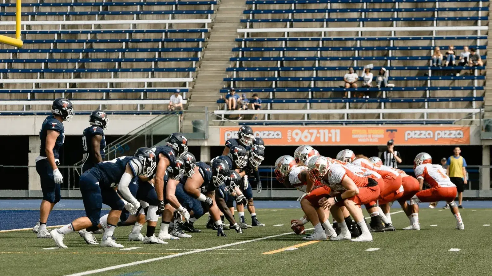 American football teams in a stand-off on a Toronto field, capturing tension.