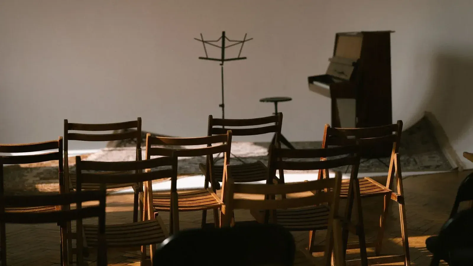 Una sala de música vacía con sillas de madera, un piano y un partitura listo para una actuación.