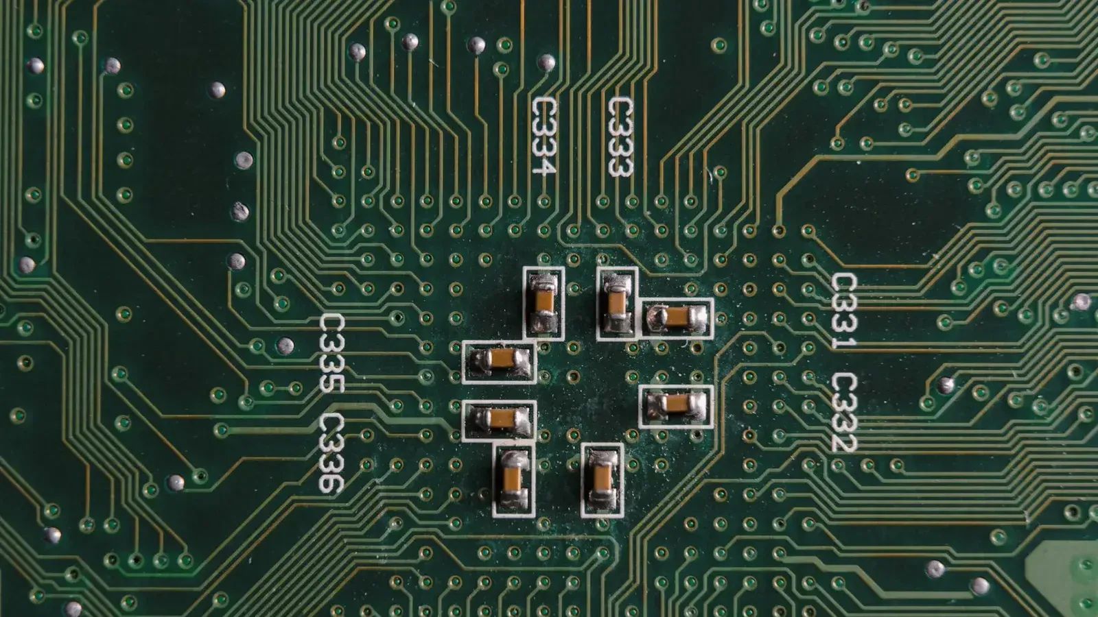 Explore el intrincado diseño y los componentes en una placa de circuito verde con condensadores y vías.