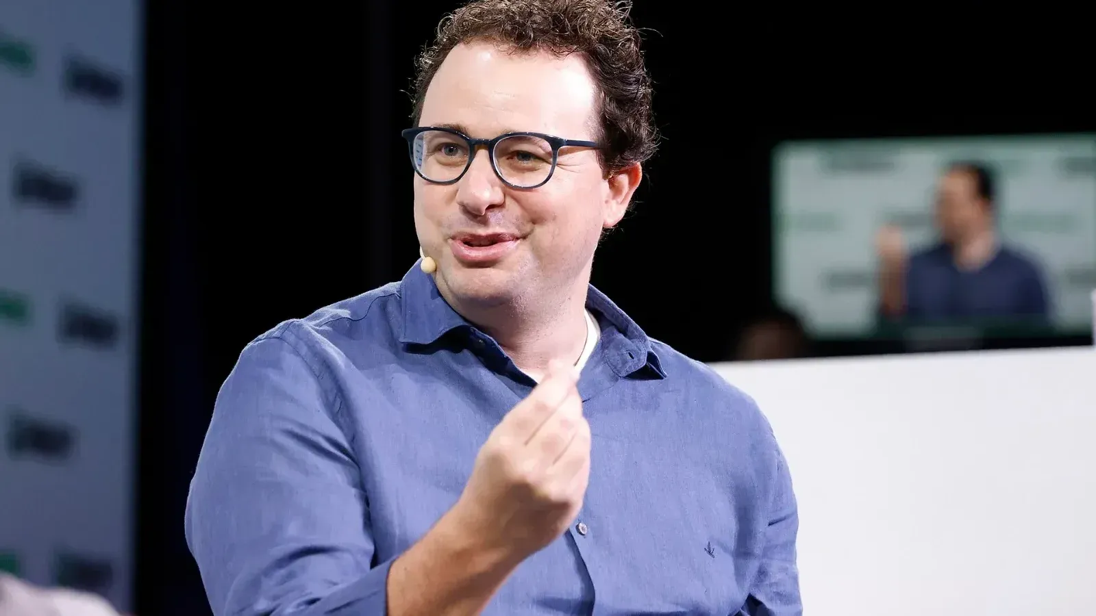 Dario Amodei, con gafas y camisa azul, habla y gesticula con una mano durante una entrevista en el escenario de TechCrunch Disrupt 2023.