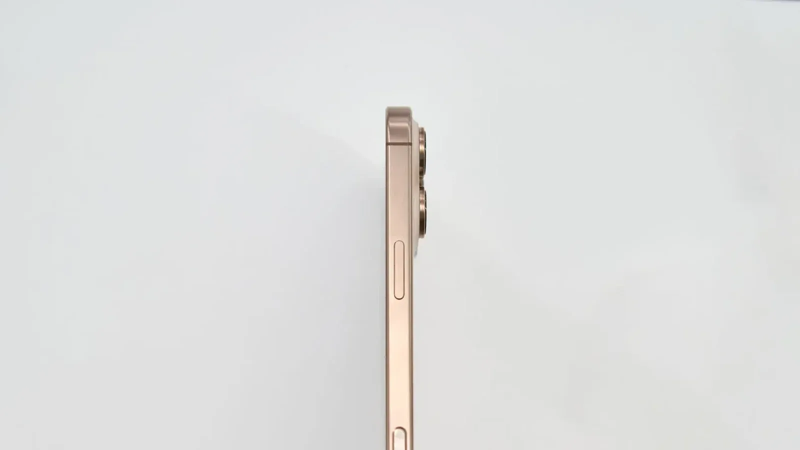 Minimalist side view of a gold smartphone on white background.
