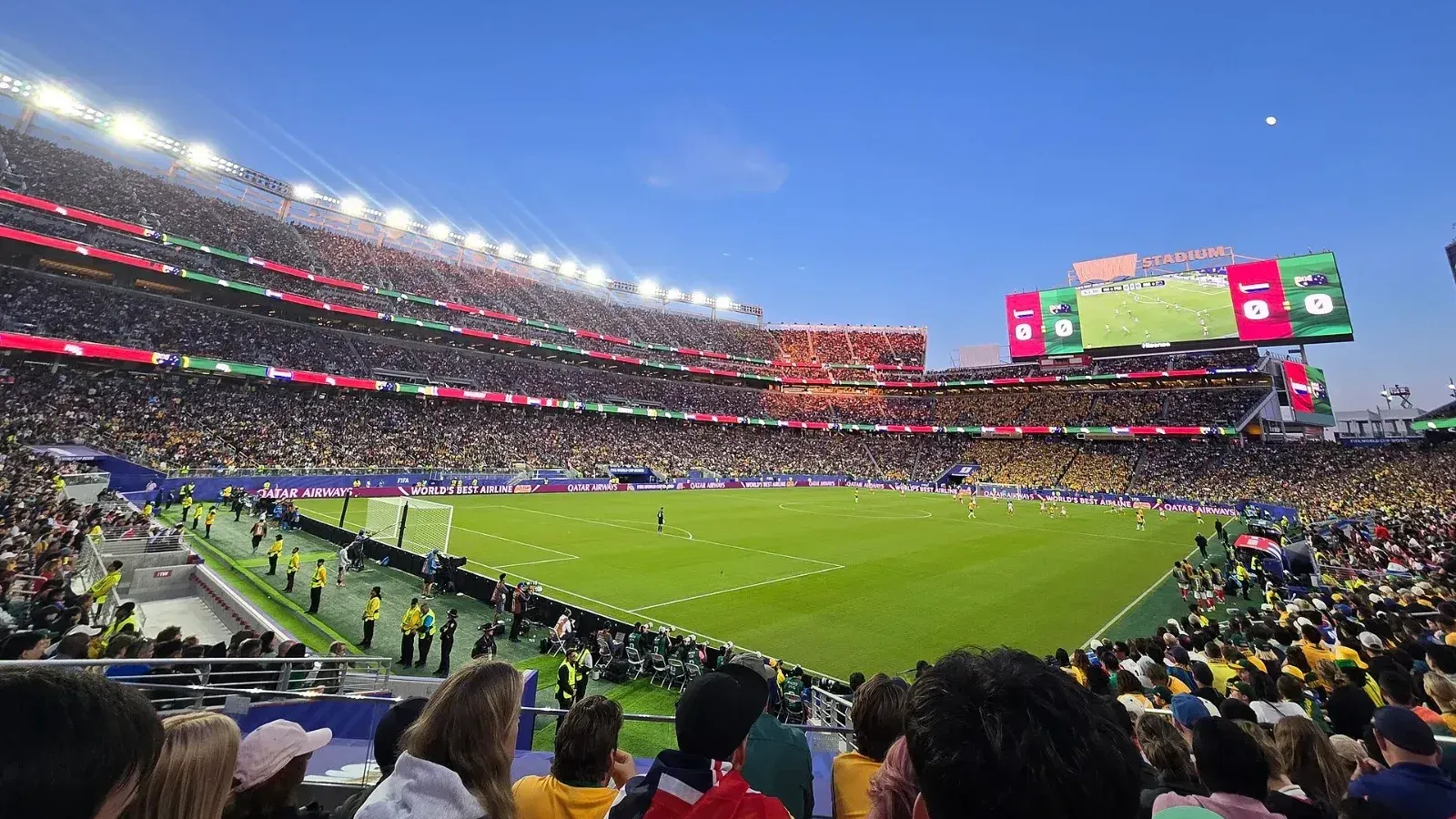Vista desde la grada del Levi's Stadium, lleno de aficionados, durante un partido del Mundial 2026 entre Australia y Paraguay, con el césped iluminado y la pantalla gigante al fondo.