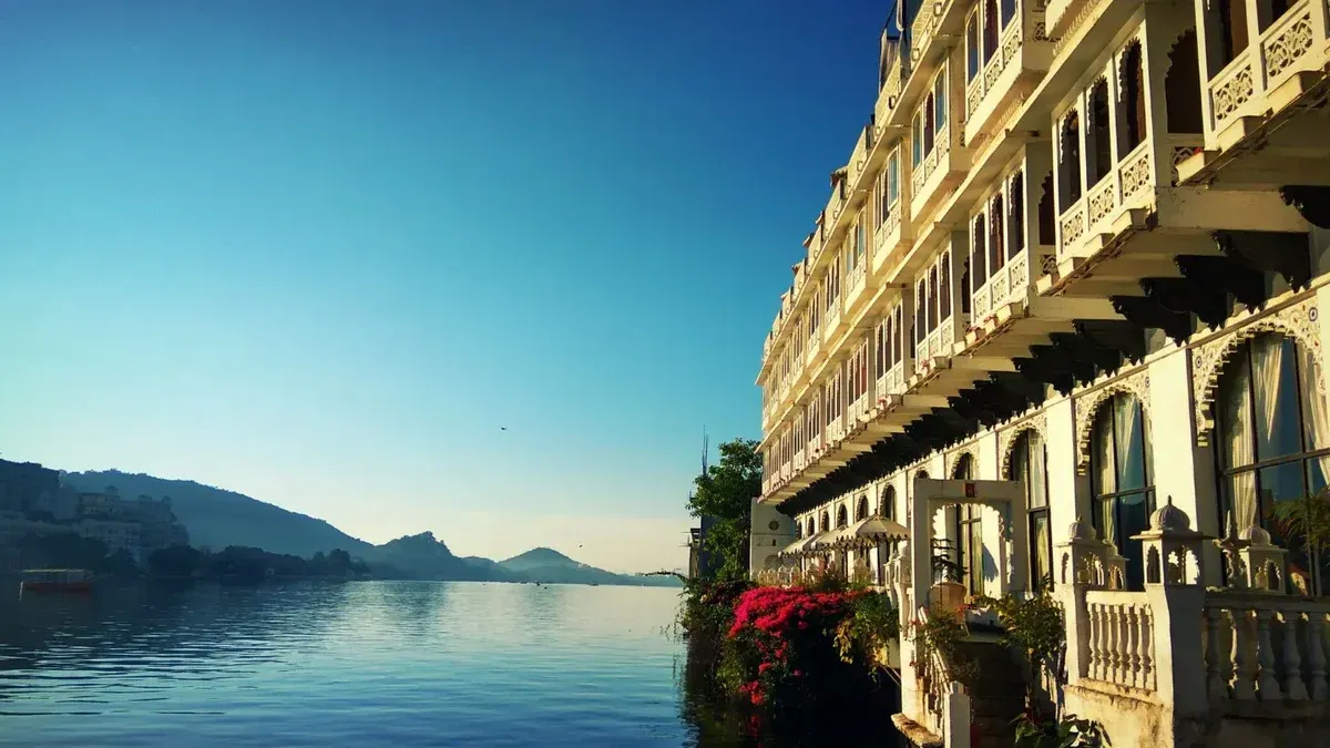 Stunning view of a lakeside palace in Udaipur, reflecting its intricate architecture on the serene water.