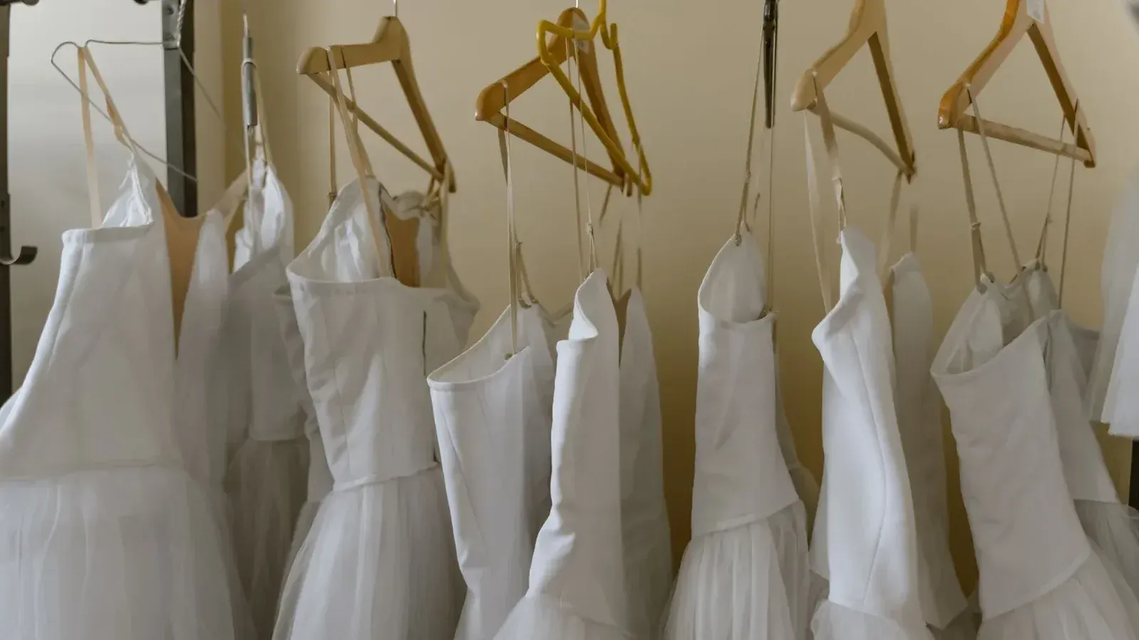 Disfraces de ballet blanco suave colgados cuidadosamente en perchas de madera en un elegante vestidor.