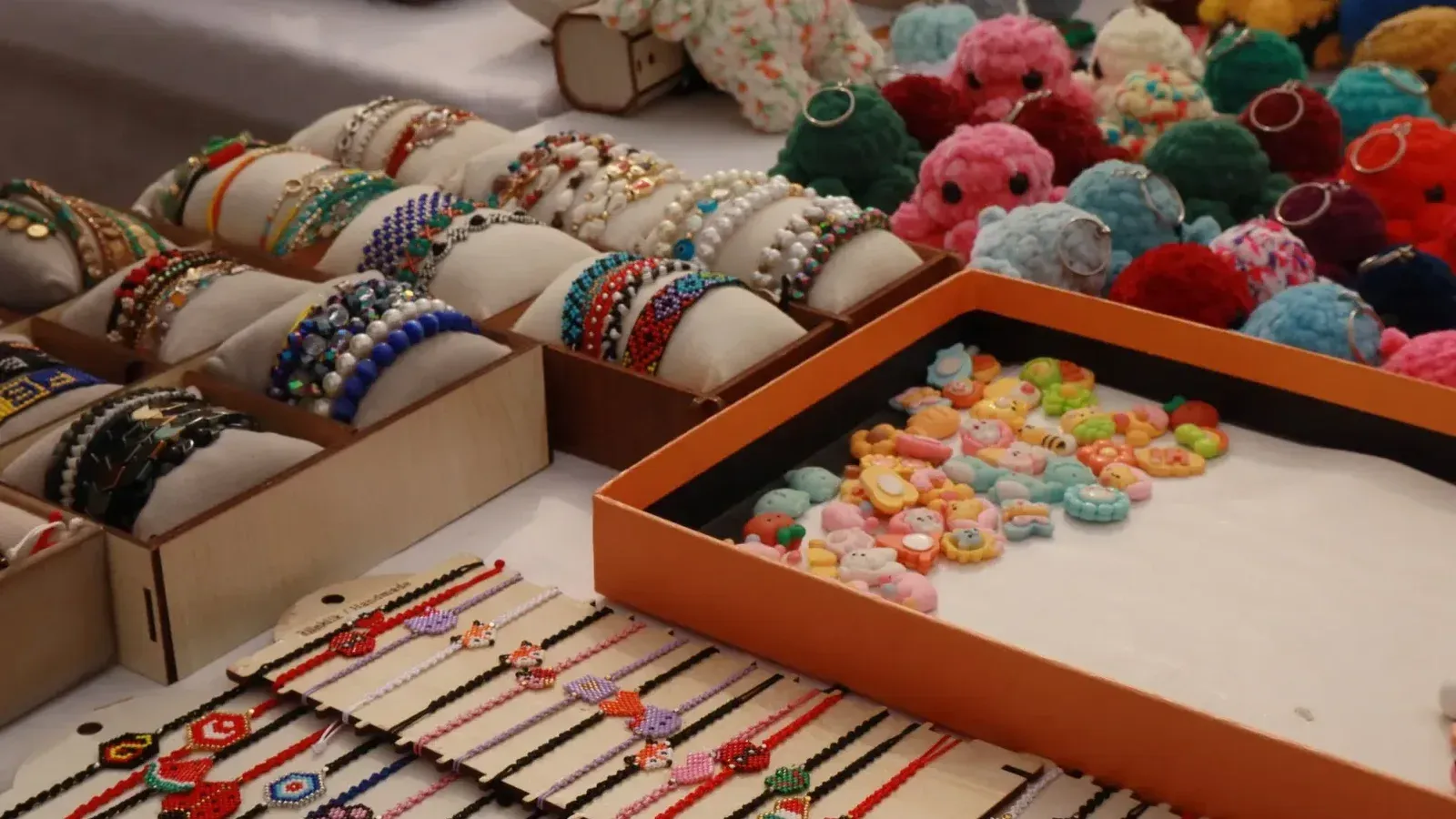 Vibrant display of handmade bracelets and crocheted keychains at a market stall.