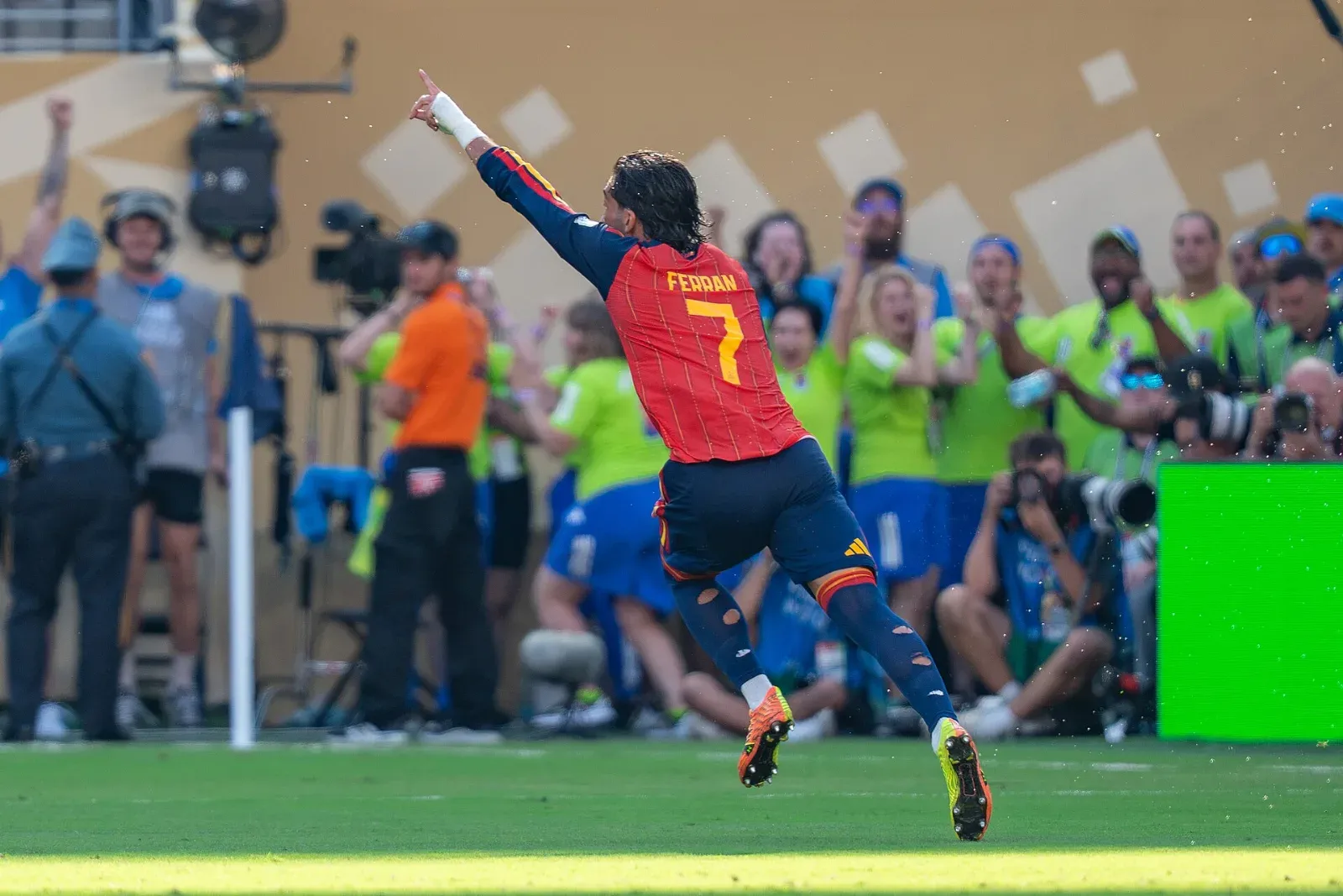 Ferran Torres, de espaldas con la camiseta roja de España y el número 7, celebra con el brazo en alto frente a fotógrafos y aficionados.