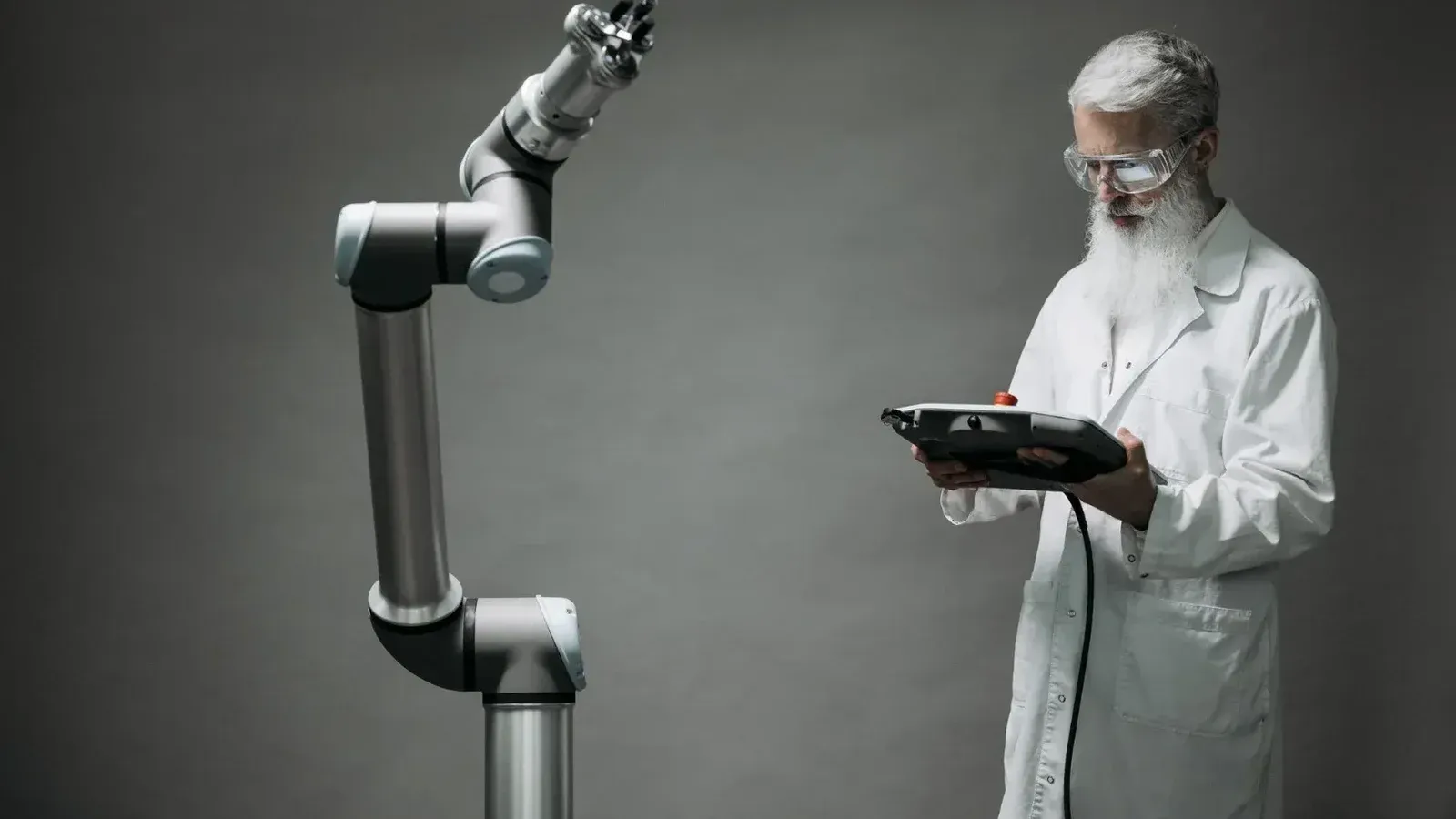 Un científico con bata de laboratorio opera un brazo robótico de alta tecnología en un entorno de laboratorio.