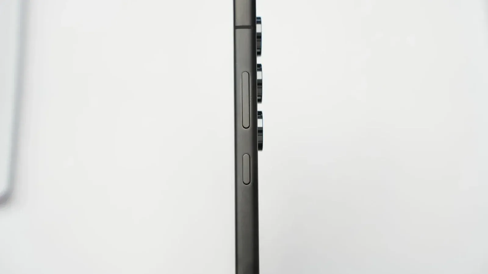 Disparo de perfil lateral minimalista de un smartphone delgado moderno que destaca sus lentes de cámara.