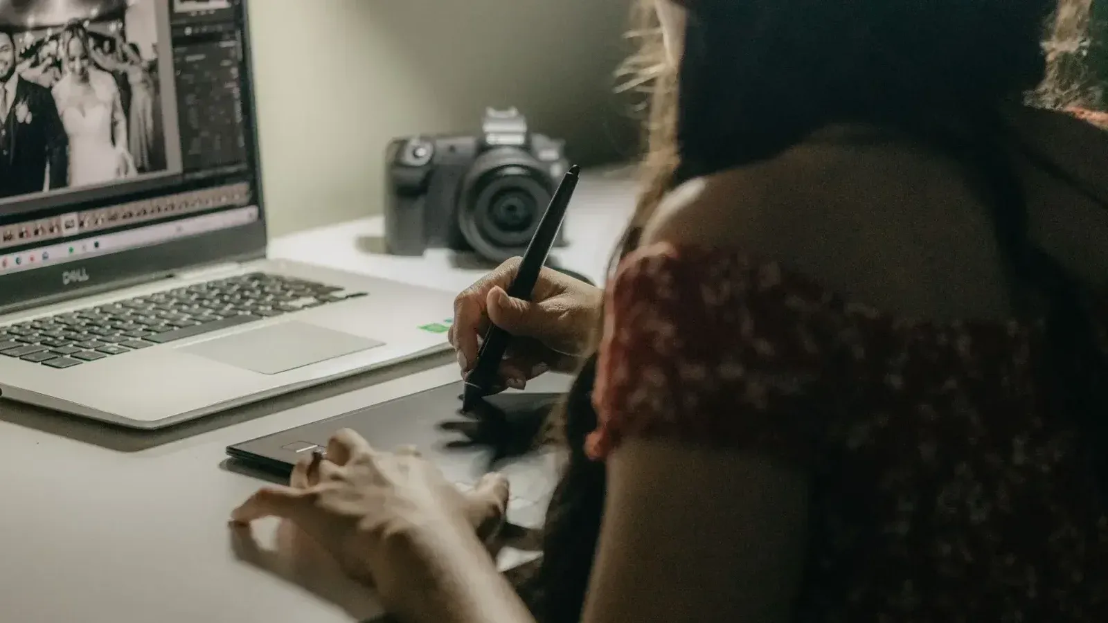 Una mujer edita fotos en una tableta y una computadora portátil en un espacio de trabajo creativo.
