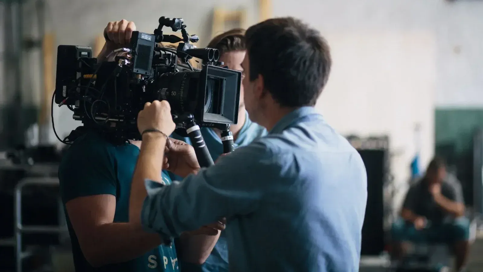 A film crew adjusting a video camera on an indoor set, focusing on technical preparation and teamwork.