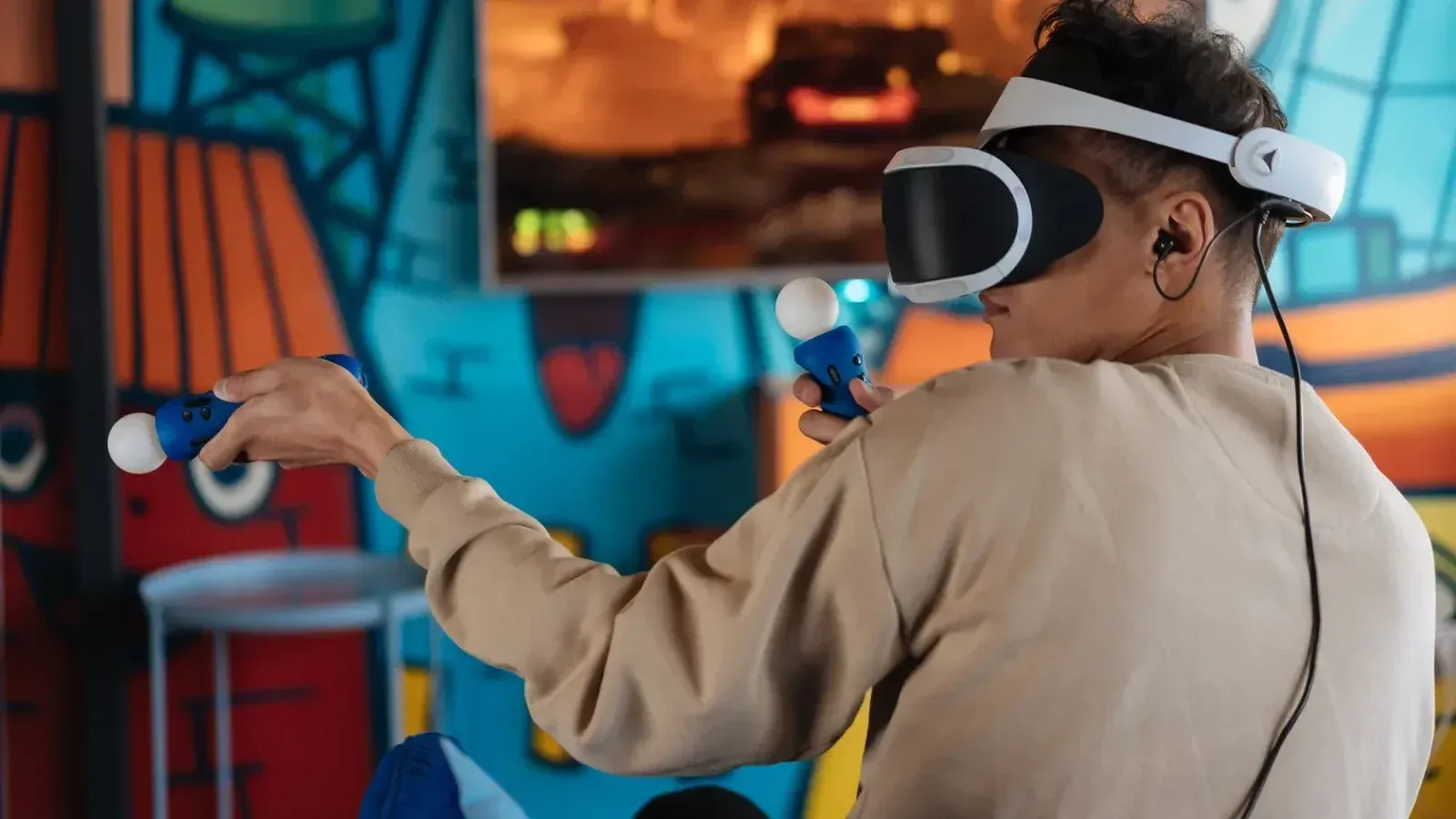 Persona disfrutando de juegos de realidad virtual con auriculares VR y controladores en una habitación vibrante.