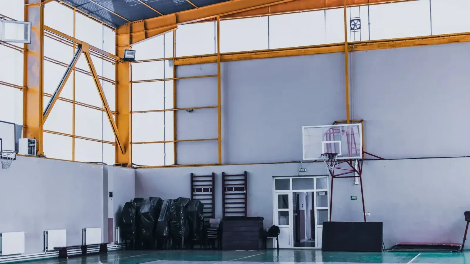Sala deportiva vacía moderna con aro de baloncesto y varios equipos de fitness durante el día