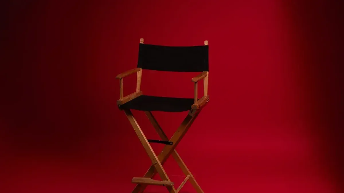 A wooden director's chair against a vibrant red backdrop, symbolizing film industry authority.