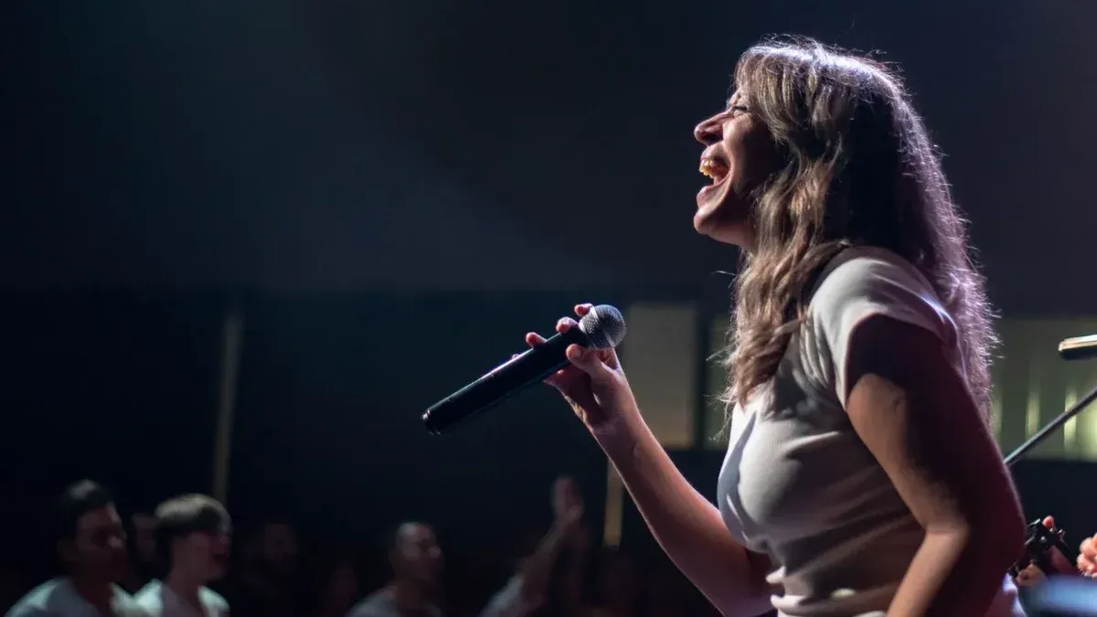 Carismática cantante femenina actuando apasionadamente en el escenario durante un concierto en vivo.