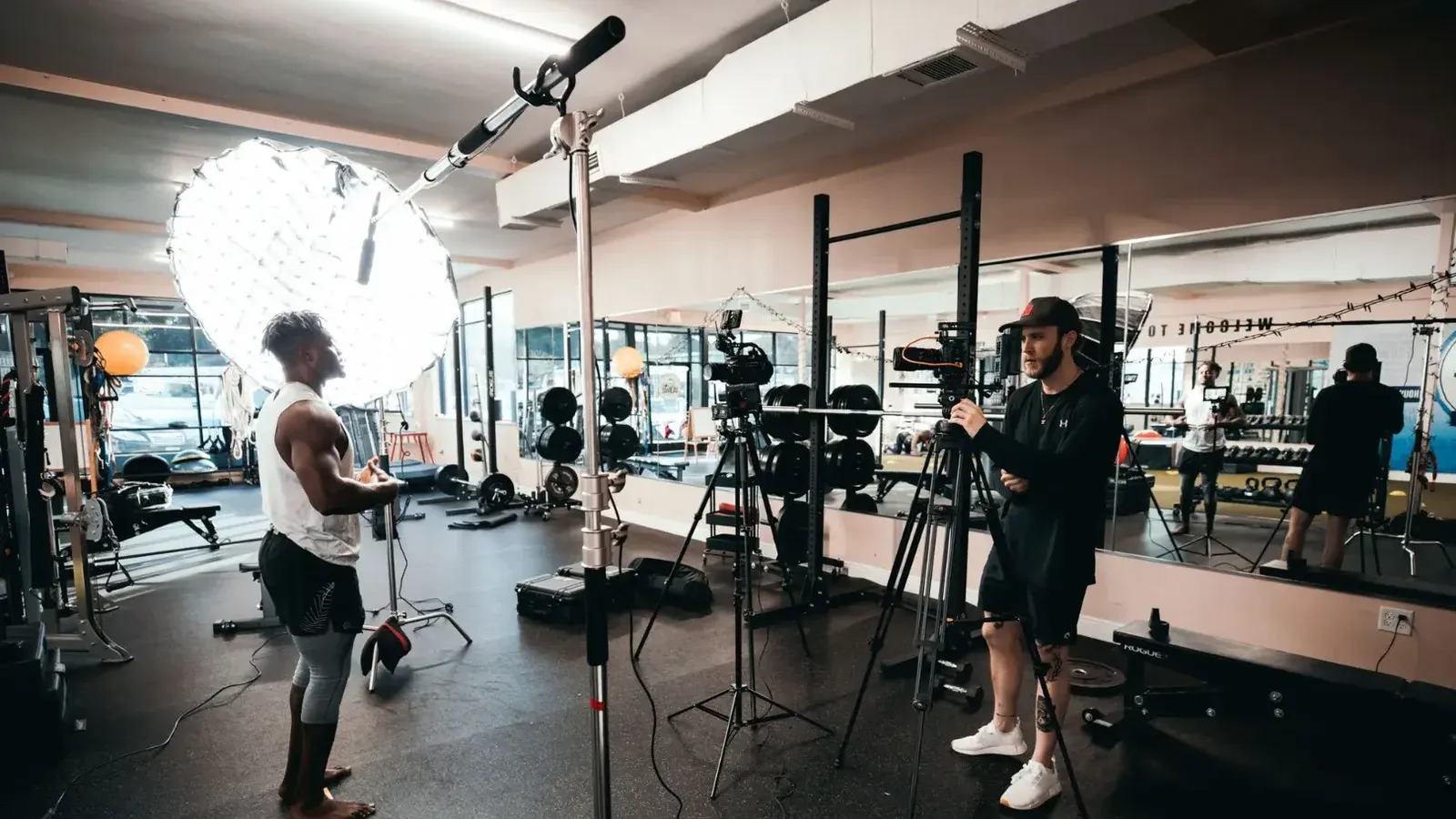 Detrás de escena de un documental de fitness siendo filmado en un gimnasio con equipo de iluminación profesional.