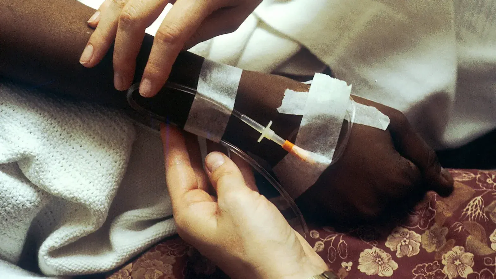 Title Chemotherapy IV Description Seen are two hands manipulating an IV for chemotherapy administration to a black patient.