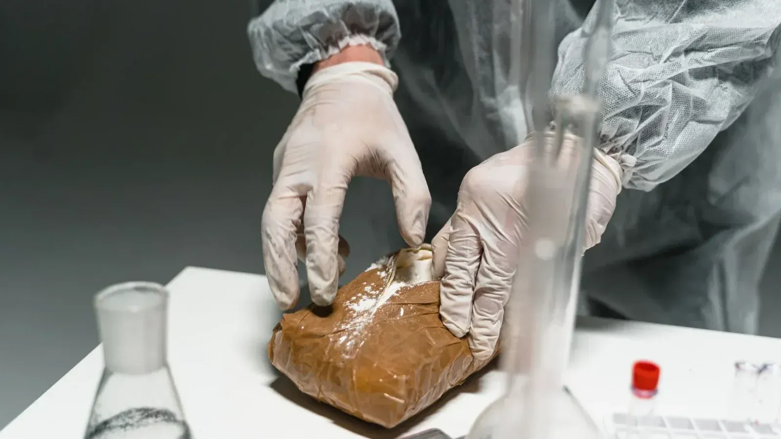 Trabajador de laboratorio analiza la sustancia en polvo en un laboratorio utilizando equipo de seguridad.