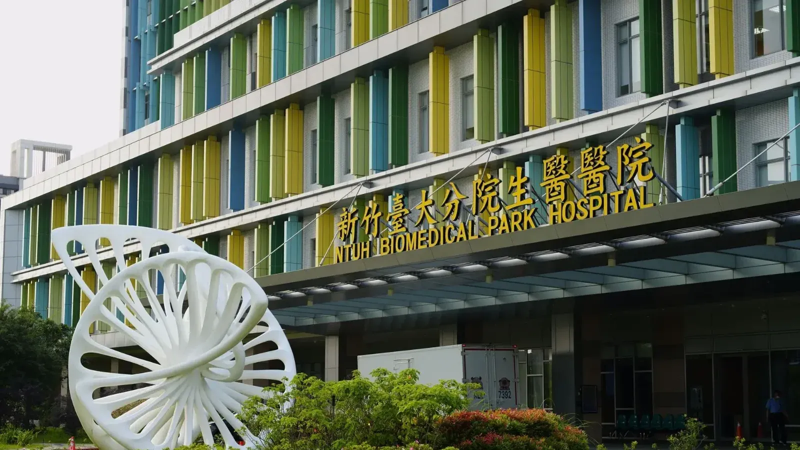 Entrada al Hospital Ntuh Biomedical Park con escultura moderna y colorida fachada en Taiwán.